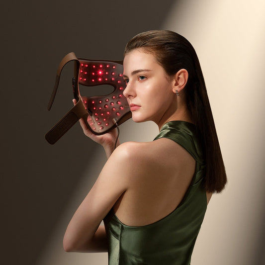Woman using JOVS 4D laser light therapy mask for facial rejuvenation, featuring red lights for skincare.